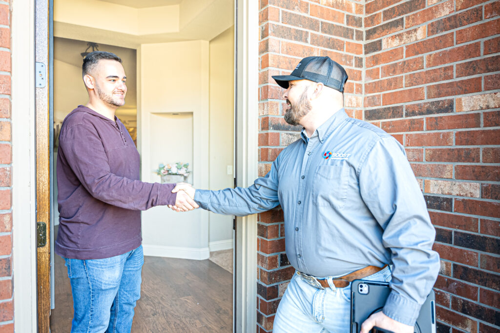 Boost Air Heating and Cooling tech with tablet greeting homeowner on porch