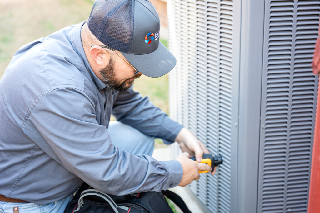 HVAC tech from Boost Air servicing outdoor AC heat pump with digital meter